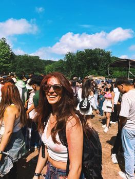 Joyful woman at a vibrant outdoor festival, enjoying a sunny day.