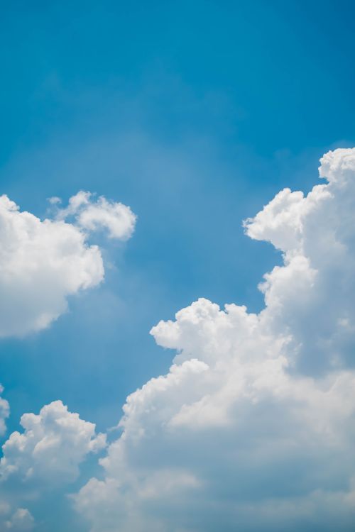 Free A bright blue sky adorned with fluffy white clouds, ideal for use in weather or nature themes. Stock Photo
