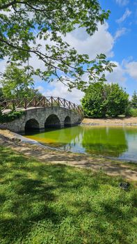 Picturesque stone footbridge crossing a calm river in a lush rural setting under a clear sky.