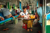 A woman selling street food on a train in Myanmar, showcasing local culture.