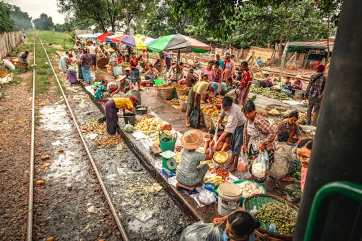 Bustling street market by railway in Yangon, Myanmar, showcasing local culture and commerce.