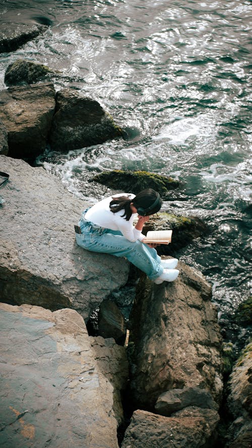 A person sitting on rocks by the ocean