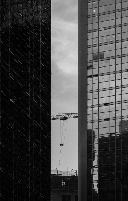 Free Black and white view of skyscrapers with a crane between them, depicting urban architecture. Stock Photo