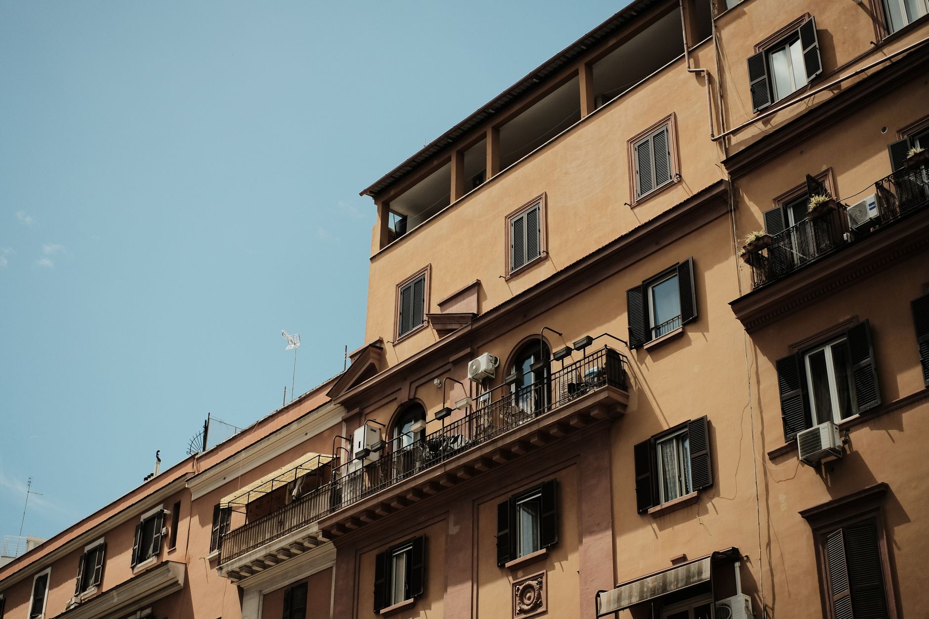 Low-angle view of traditional Roman apartments with classic architecture and balconies in Rome, Italy.