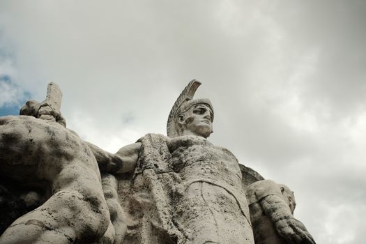 Captivating low-angle shot of a Roman sculpture against a dramatic sky in Rome, Italy.