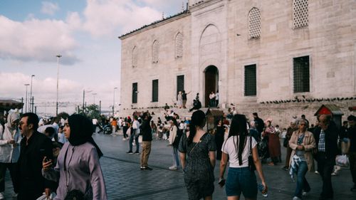 Free Bustling street scene in Istanbul with diverse people and the historic Yeni Mosque in the background. Stock Photo