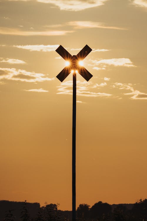 A railroad crossing sign with a sunset in the background
