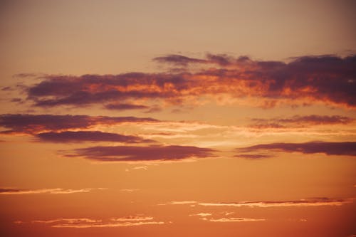 A sunset with clouds and a plane flying