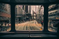 透过电车窗户，可以看到香港一条繁忙的街道，两旁高楼林立，公共交通穿梭其间
