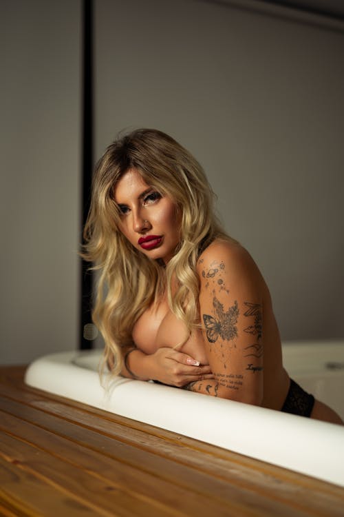 A woman with tattoos and piercings sitting in a bathtub