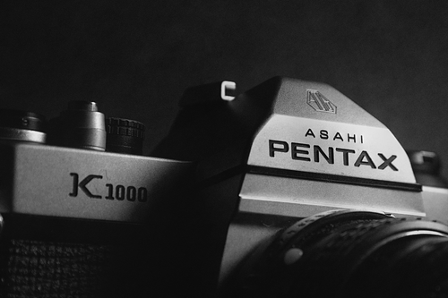 Free Black and white close-up of Asahi Pentax K1000 film camera, emphasizing its vintage appeal. Stock Photo