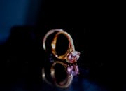 深色表面上，粉红色宝石戒指的特写镜头倒影优雅，尽显奢华与优雅