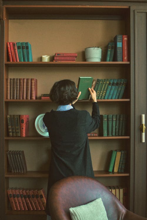 A woman is looking at books in a bookcase