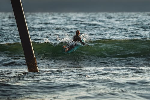 A surfer rides a wave under a pier