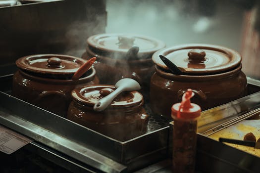 Close-up of steaming traditional clay pots with utensils on a stove, creating a cozy kitchen ambiance.