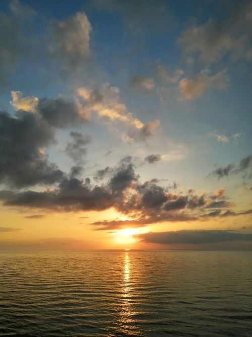 Free Stunning ocean view at sunset with vibrant skies and dramatic clouds reflecting on water. Stock Photo