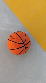 Vibrant orange basketball on a geometric court with yellow accents, minimalistic and modern.