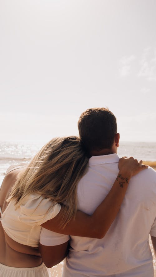 A couple hugging on the beach with the ocean in the background