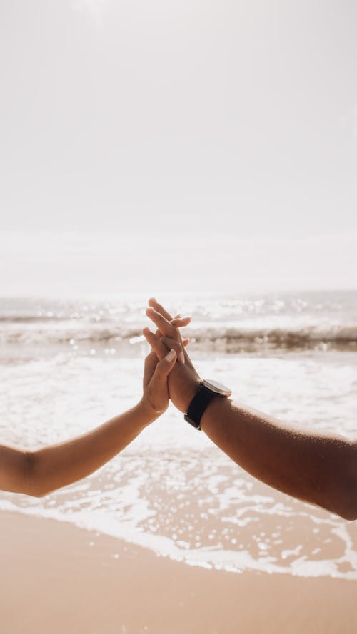 Two people holding hands on the beach