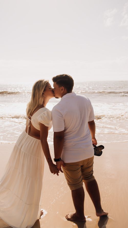 Free A young couple shares a romantic kiss on a sunny beach, capturing love and connection. Stock Photo