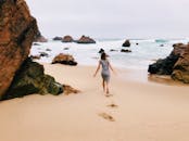 在葡萄牙科雷斯的岩石海滩上，一名妇女正悠闲散步，享受着完美的冒险环境