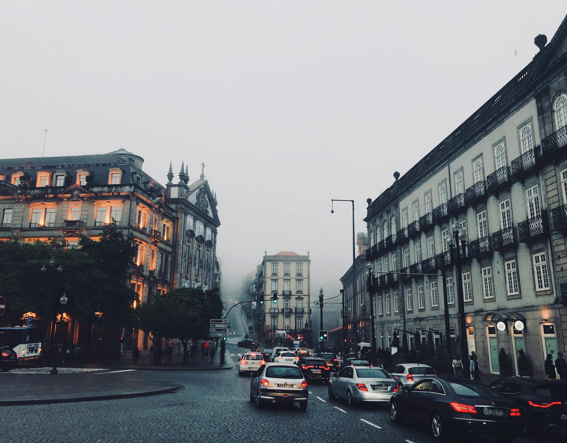 Foggy city street in Porto with historic architecture and busy traffic.