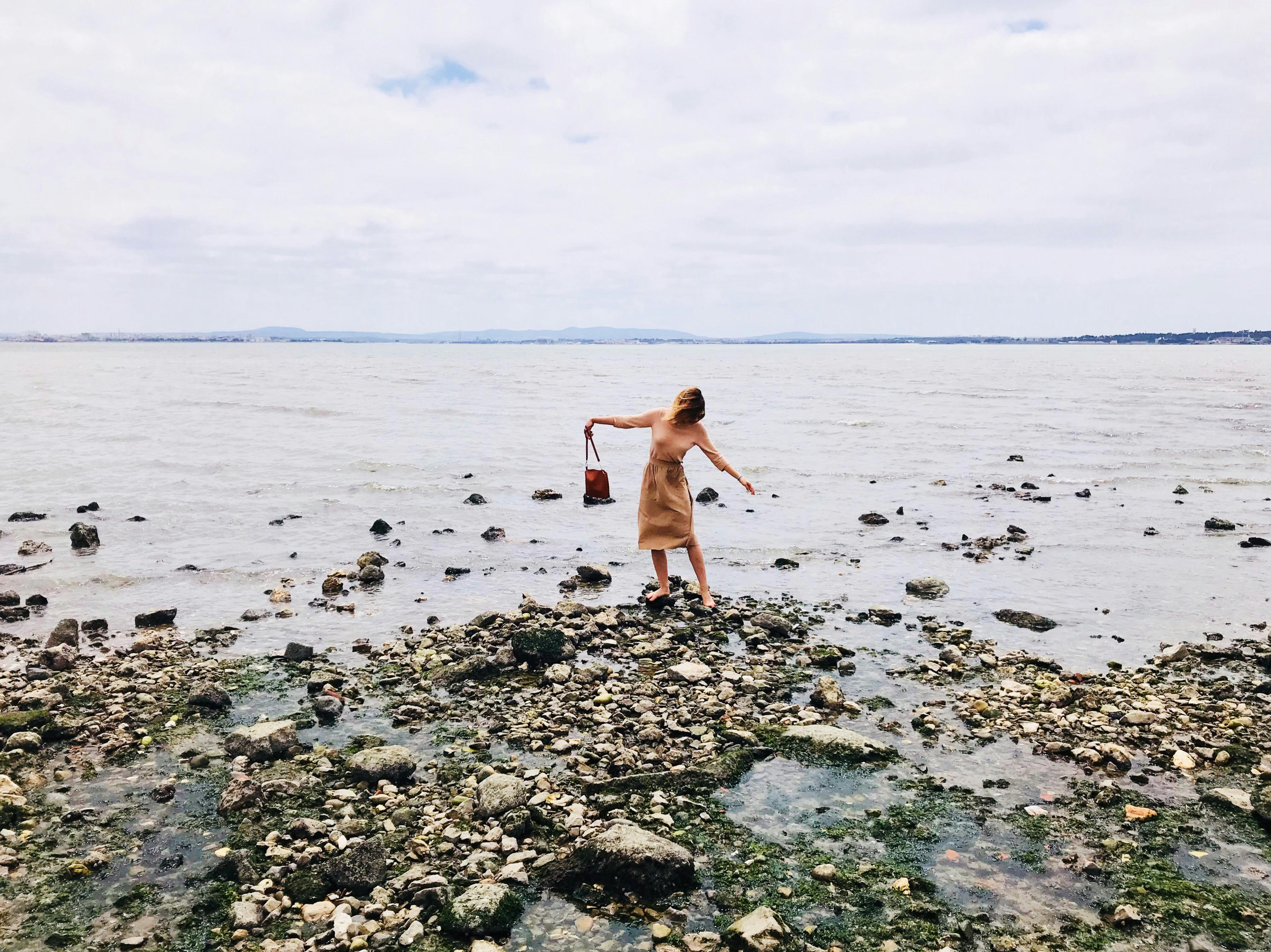 photo of a woman standing on a rocky seashore