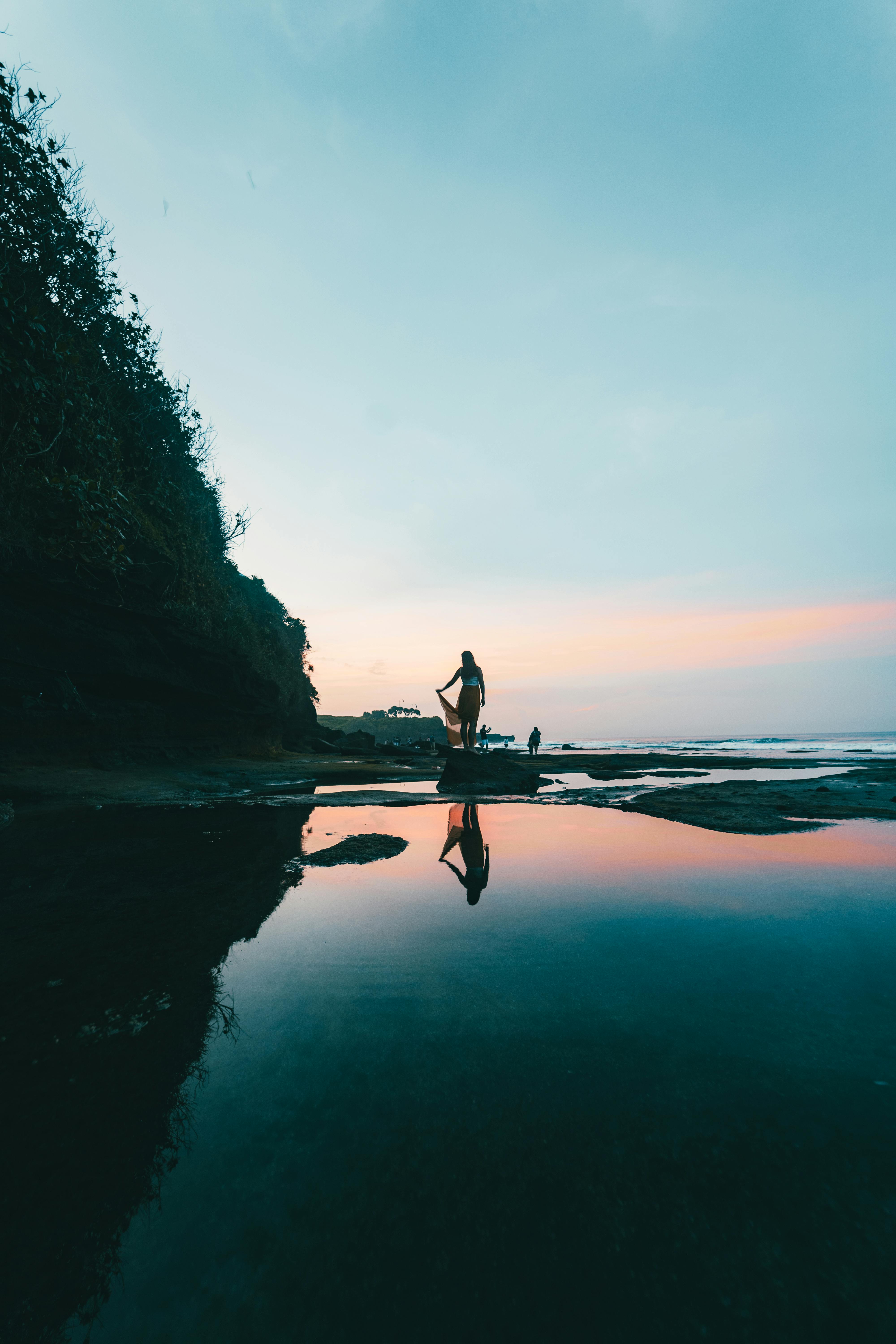 woman standing at the beach during sunset