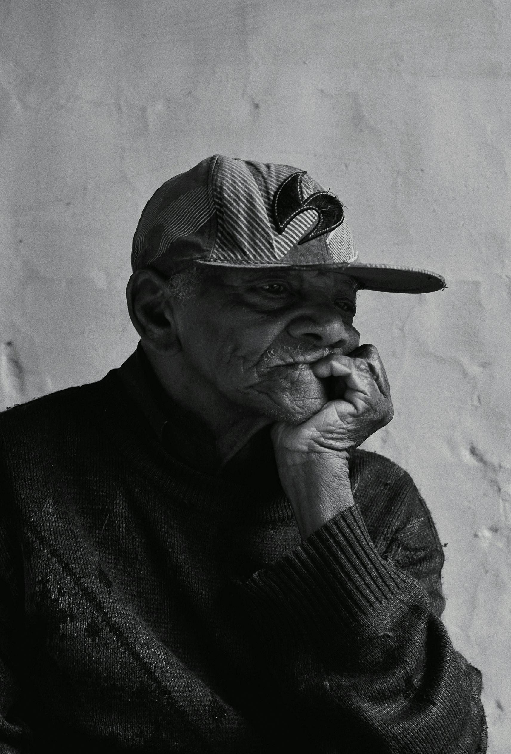 portrait photo of elderly man leaning chin on his hand palm