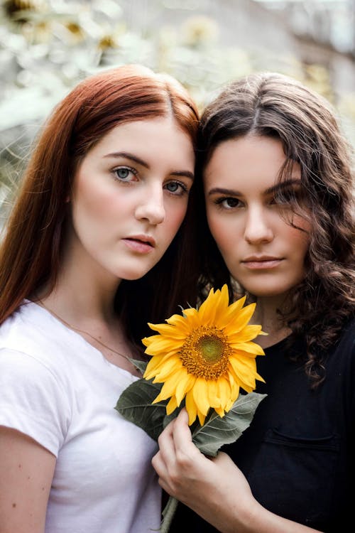 Photo of Two Women Holding Yellow Flower