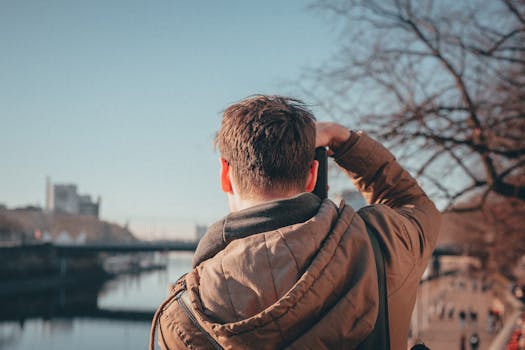 一个穿着夹克的男子，在秋日阳光明媚的一天，捕捉到了风景优美的河景