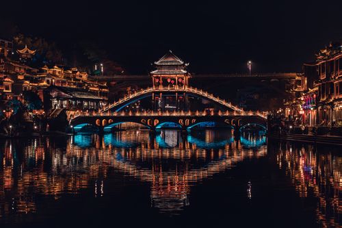 Free Stunning night view of Fenghuang Bridge in Xiangxi, China, with vibrant reflections. Stock Photo