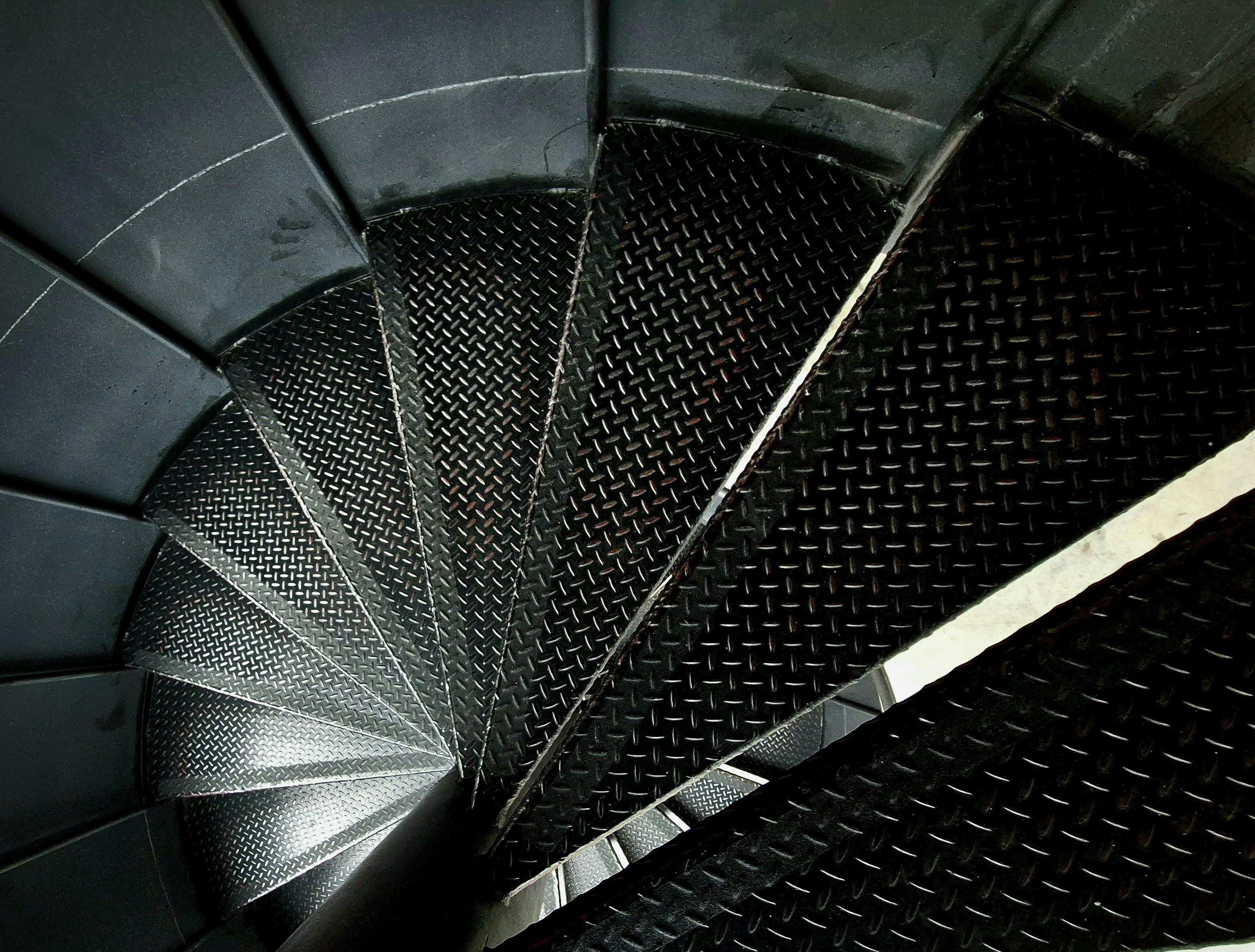 A spiral staircase with metal bars and a black background