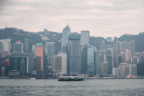 Free Panoramic view of Hong Kong's skyscrapers from Kowloon, featuring a ferry crossing the harbor. Stock Photo