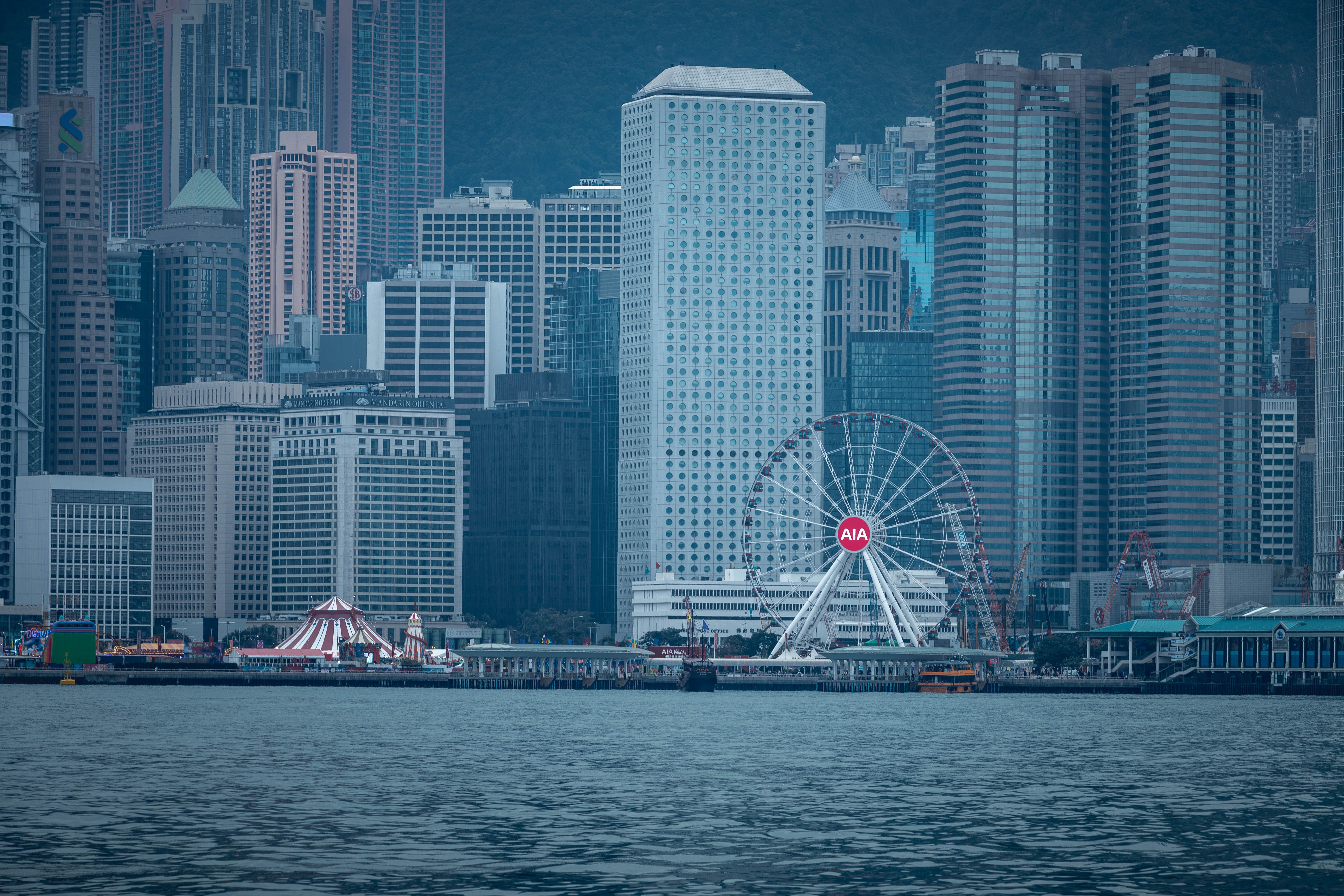 A vibrant cityscape featuring towering skyscrapers and a ferris wheel along the waterfront.