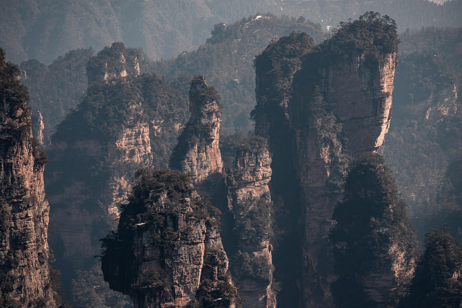 Explore the stunning rock formations of Zhangjiajie, Hunan, China at sunset, adding drama to the landscape.