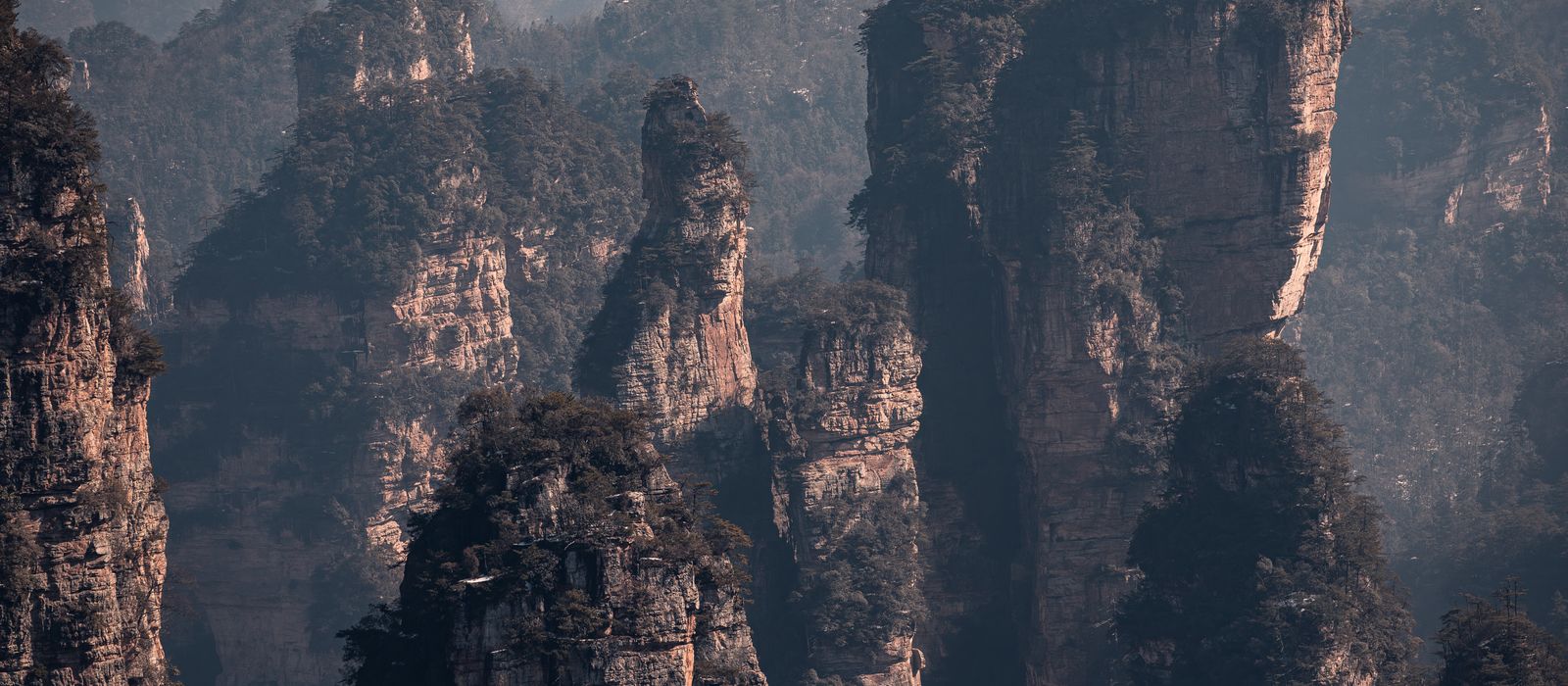 Explore the stunning rock formations of Zhangjiajie, Hunan, China at sunset, adding drama to the landscape. — flights from Shanghai to Dayong