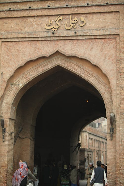 A group of people walking through an archway with arabic writing on it