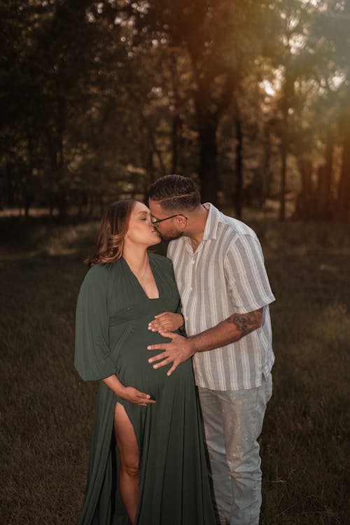 A pregnant couple in a field at sunset