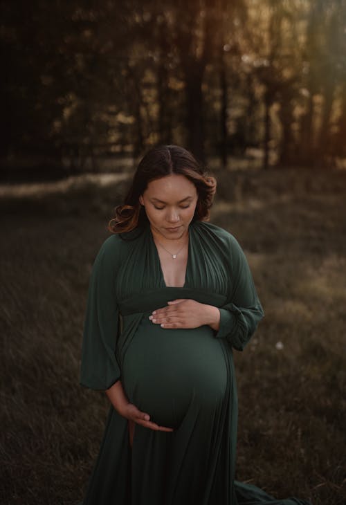 A pregnant woman in a green dress in a field