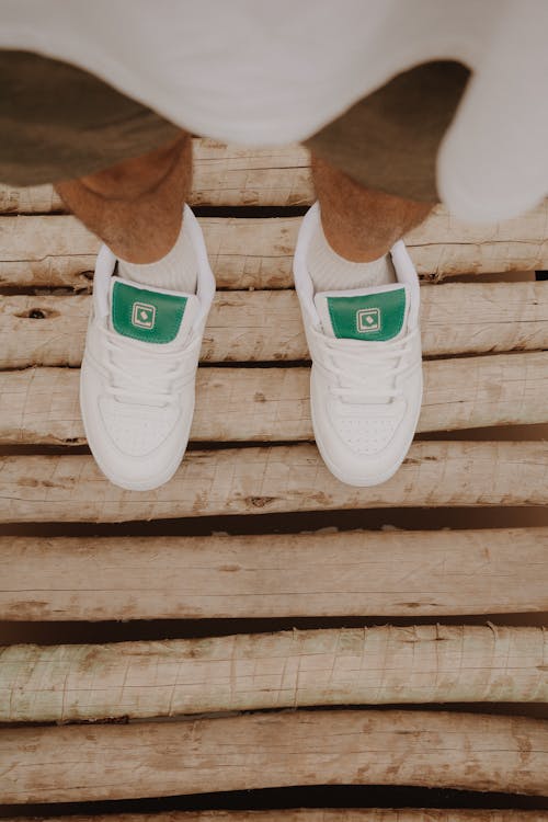 Legs in White Sneakers on a Wooden Pier