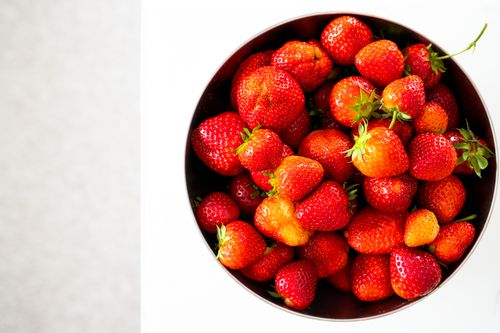 Free Vibrant red strawberries in a bowl on a white background, perfect for food photography. Stock Photo