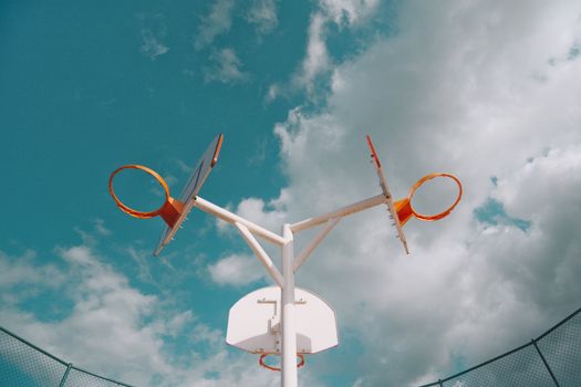 Artistic view of a unique basketball hoop set against contrasting clouds and sky.