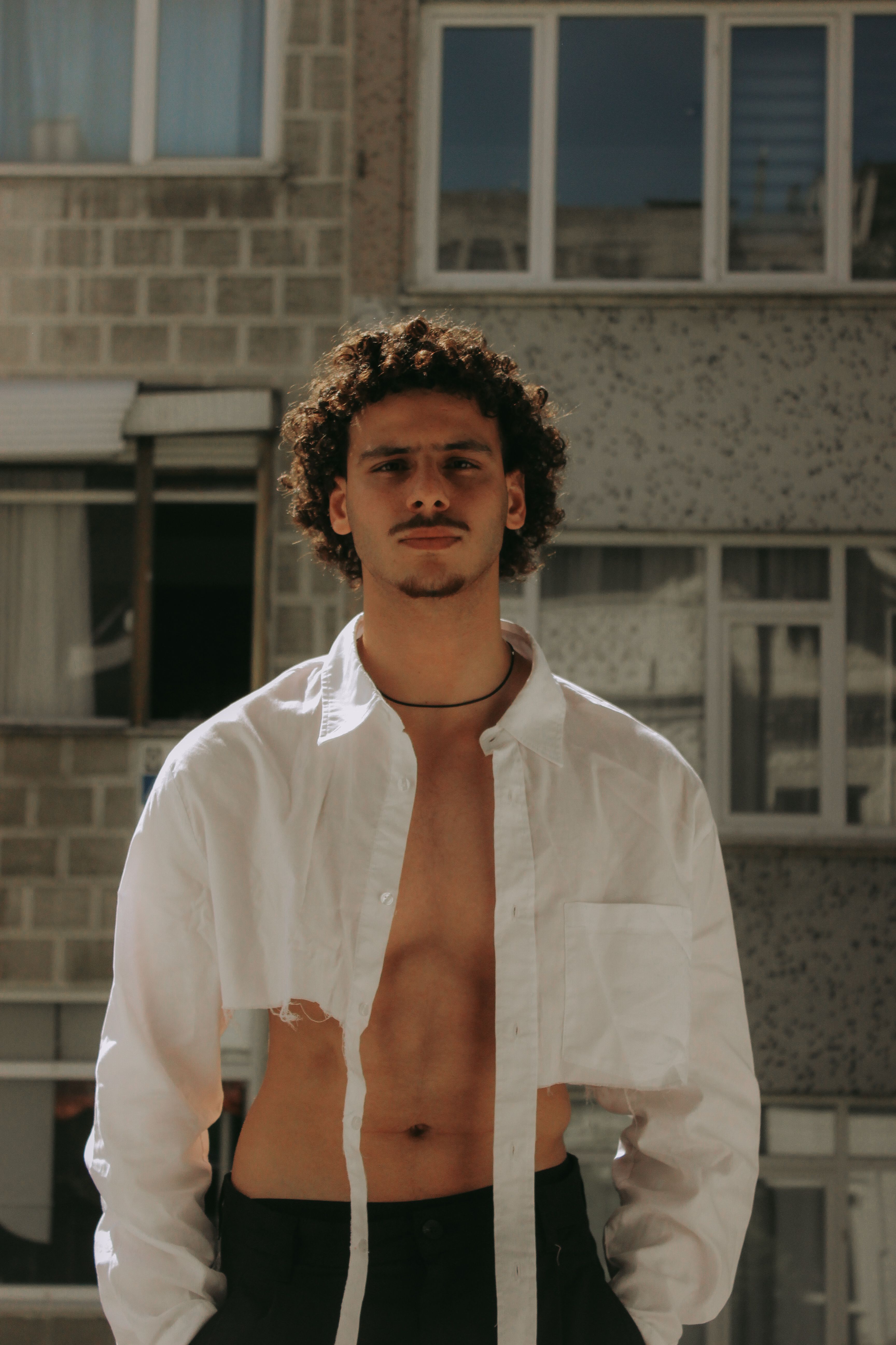 Portrait of a young man standing outdoors with an urban backdrop.