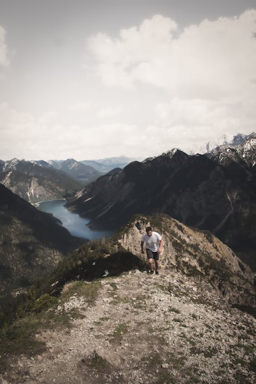 A person standing on top of a mountain looking at a lake
