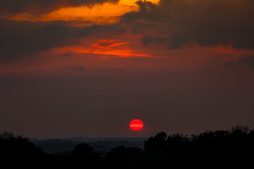 A red sun setting over a dark sky