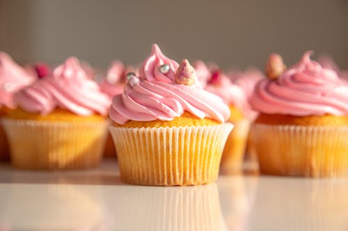 Pink cupcakes with pink frosting on a white surface