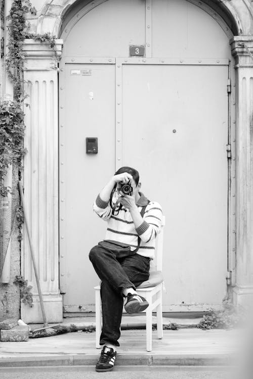 A man sitting on a chair taking a picture