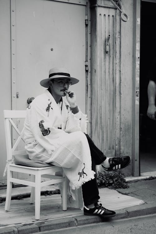 Man in Hat and Robes Sitting and Smoking