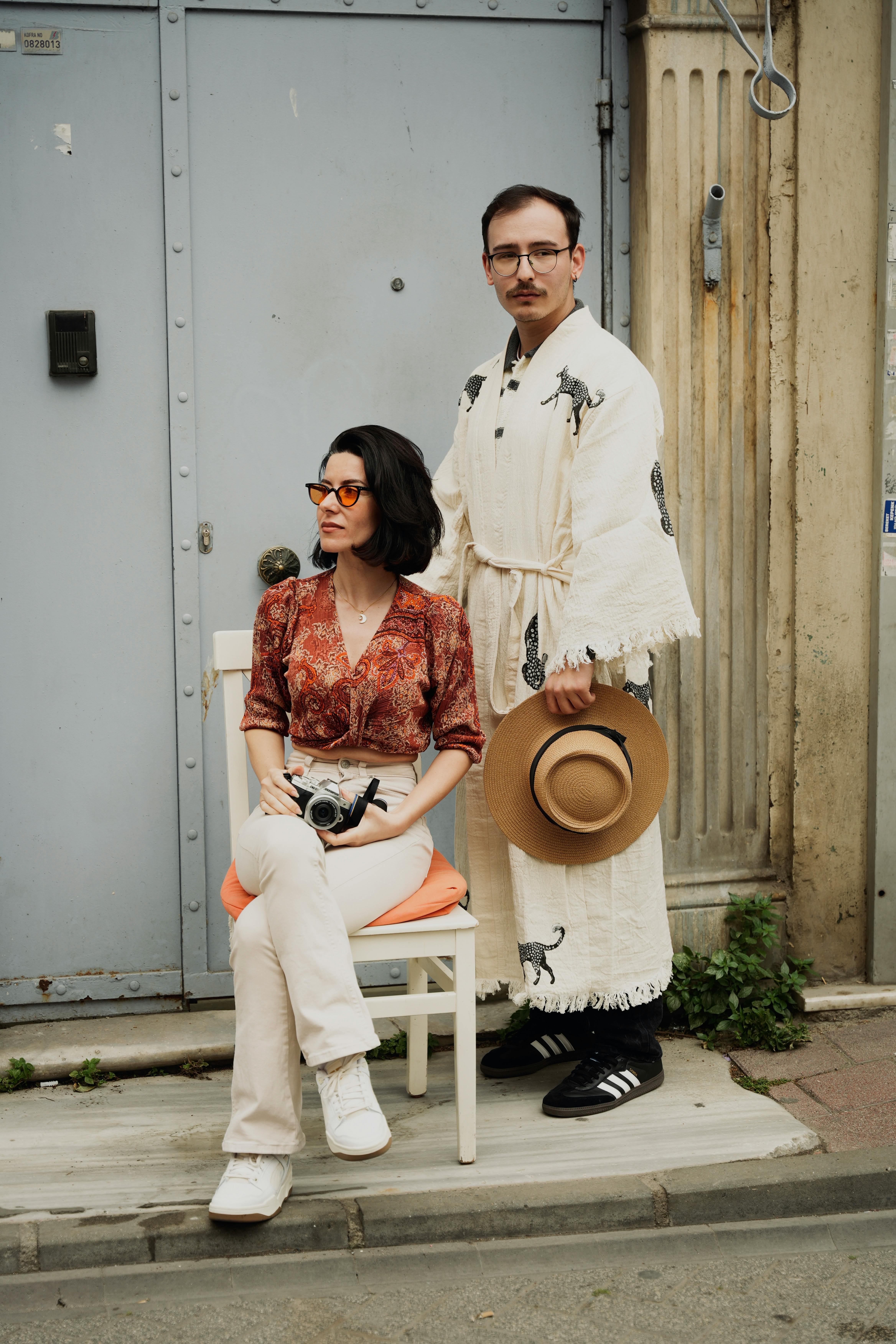 man in robes standing with hat and woman sitting on chair